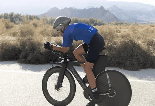 Male triathlete riding a Specialized S-Works time-trial bike in an aerodynamic position during a desert road ride